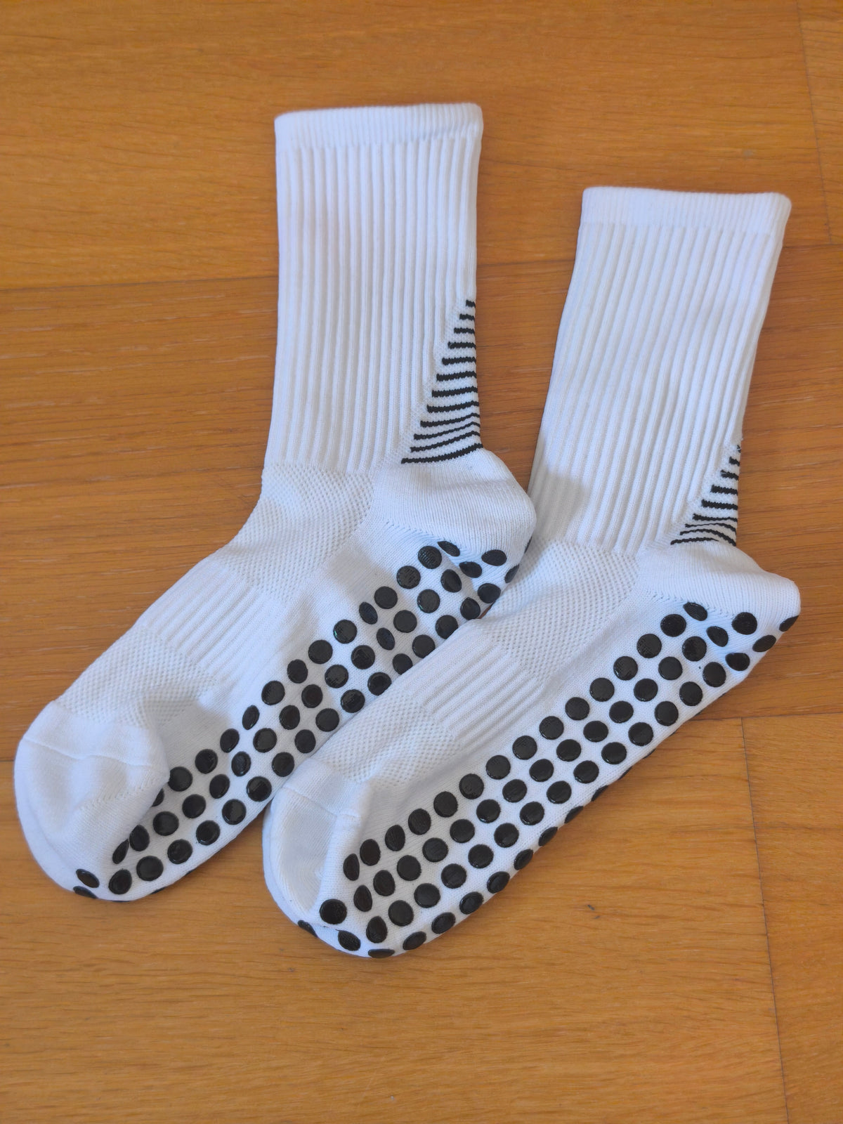 Chaussettes de foot antidérapantes blanches posées à plat, semelle à picots silicone visible